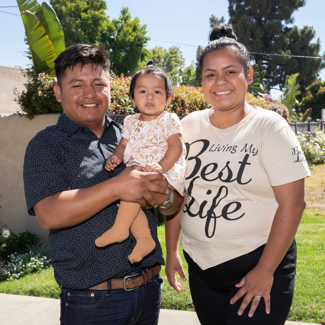 Two parents holding their young child outdoors